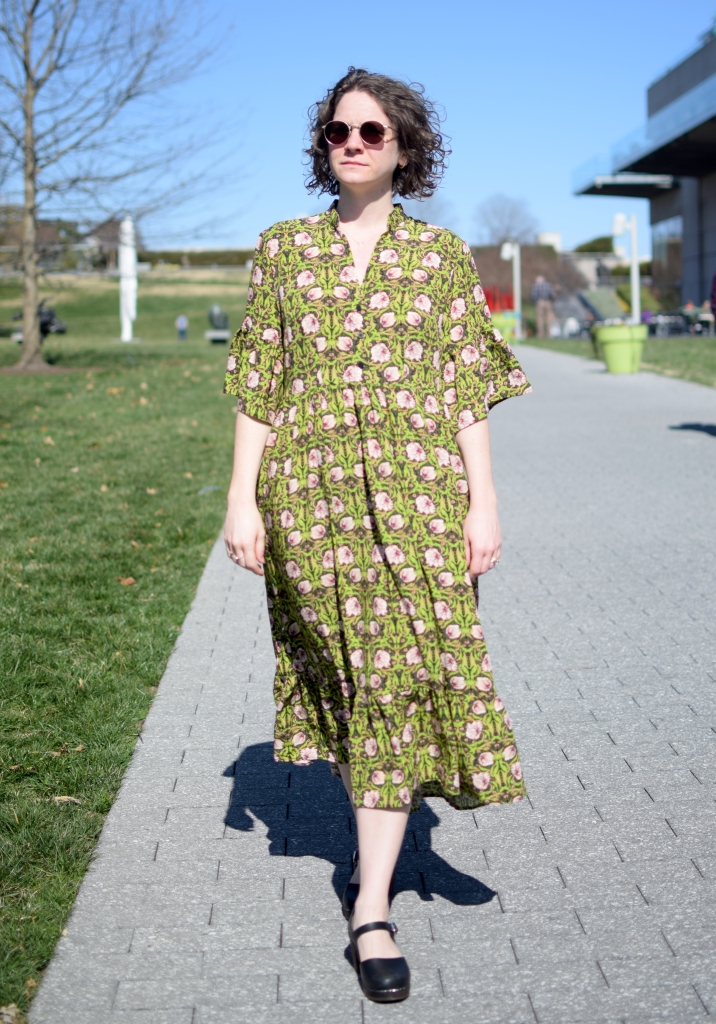 a girl wearing a green and pink floral dress in the bright sun.